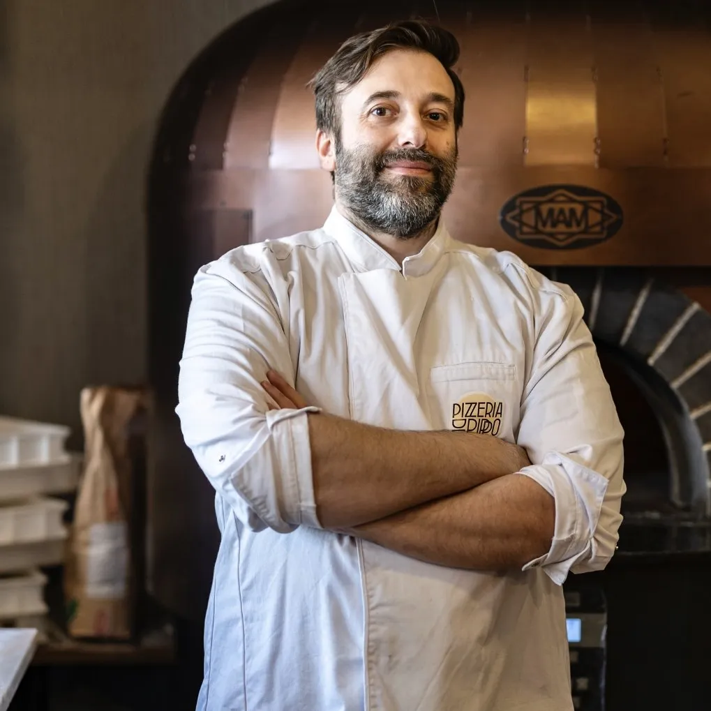 Giuseppe Irace de braços cruzados em frente ao seu forno de lenha