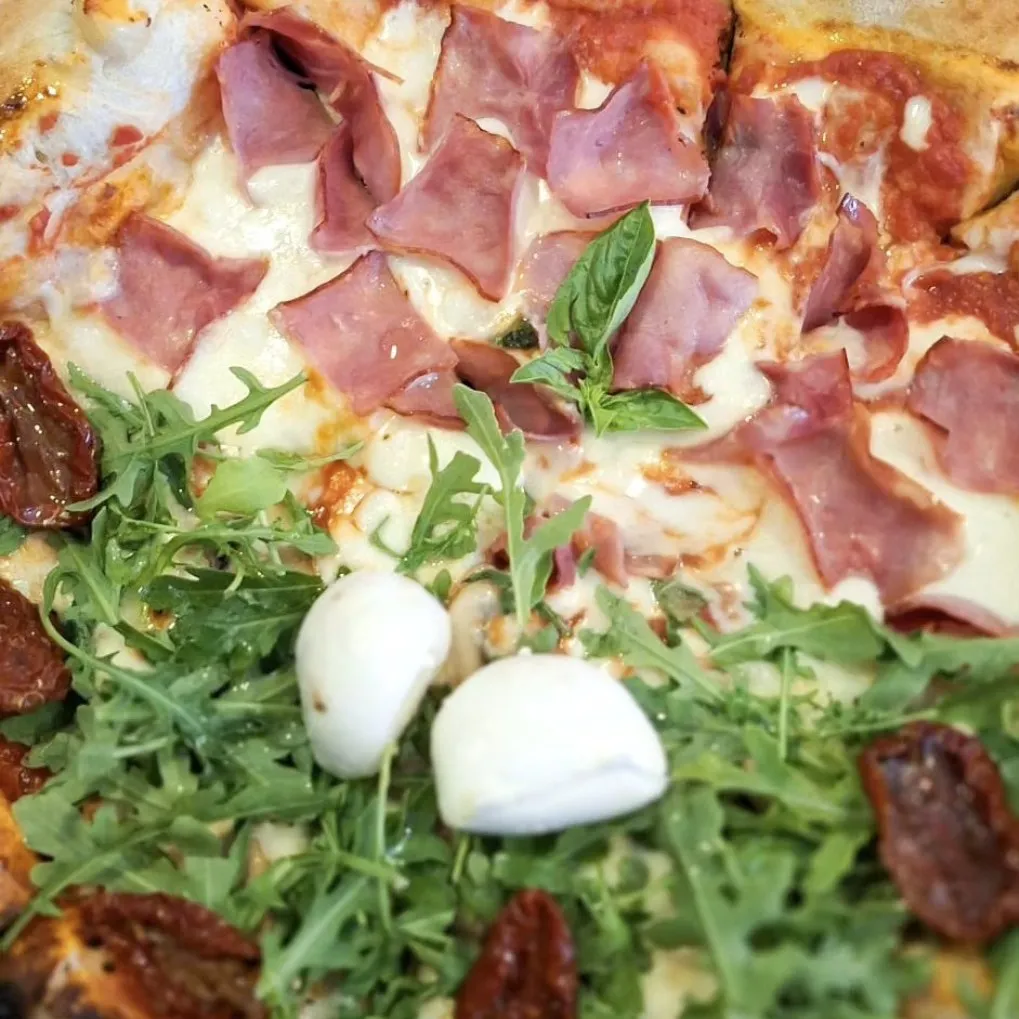 Pizza feita metade Di Lily, metade Toscana